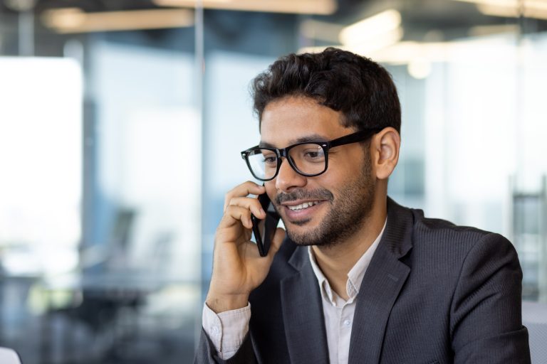 Young successful arab businessman boss talking on phone close up, man smiling contentedly inside