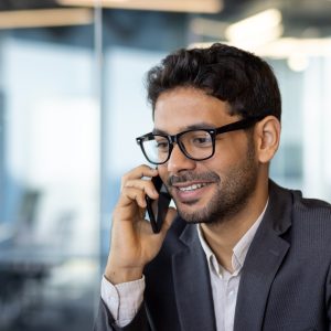 Young successful arab businessman boss talking on phone close up, man smiling contentedly inside